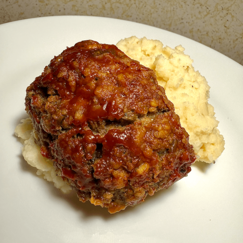 Easy gluten-free and low FODMAP meatloaf sliced and served on a plate with a side of vegetables.